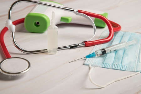 Medical instruments in the form of an infrared thermometer, a syringe with a virus vaccine, a...