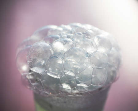 A glass with soap foam and bubbles on a blue background.