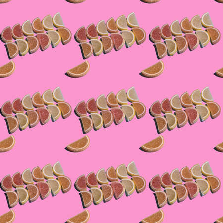 Seamless candy pattern on a pink background of jelly marmalade in the form of pieces of citrus fruits. Top view.の写真素材