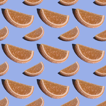 Decorative seamless candy pattern of fruit marmalade in the shape of a lemon slice on a blue background. Jelly sweet candies. Top view.Flat spoonの写真素材