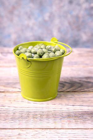 Frozen green peas in a green bucket on a wooden table.の写真素材
