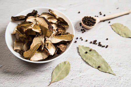 On a gray table, spices and dried porcini mushrooms are served before cooking. Dishes of Russian...