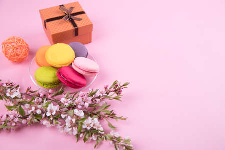 Macaroons cookies on a paper pink background with branches of a flowering shrub.の写真素材