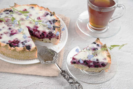 He placed it on top of a white plate with a homemade berry pie and a cup of tea.