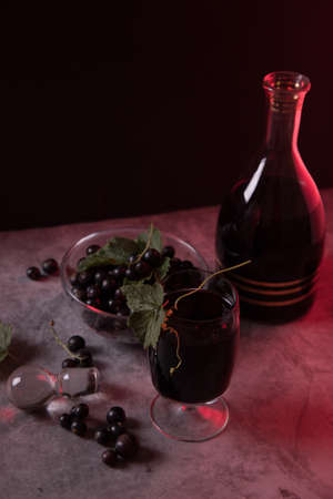 On a dark background, homemade blackcurrant liqueur in a glass from a decanter.の写真素材