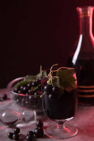 Close-up of a glass with homemade black currant liqueur with berries on the glass. Low keyの写真素材
