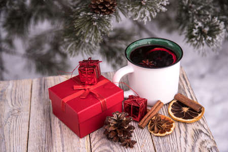 Boxes with gifts next to a warming cup of mulled wine on a winter background.