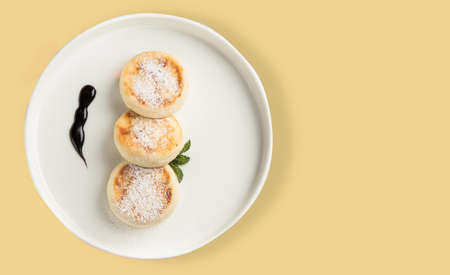 A plate with a morning breakfast - cheesecakes on a yellow background.