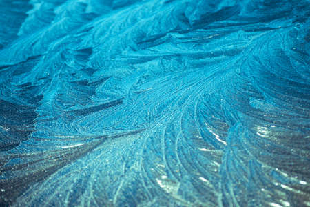 Beautiful closeup of icy frost patterns on the car in sunriseの写真素材