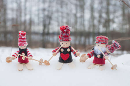 Christmas background with four gnomes in knitted hats on skis in snowy landscapeの写真素材
