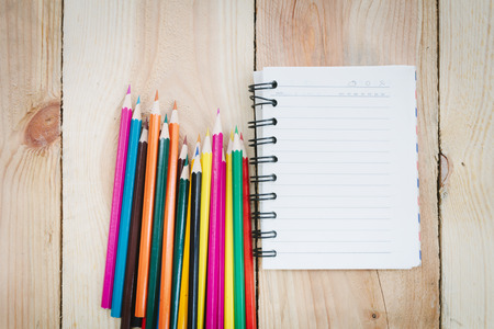 Note book and color pencils on wooden background - Vintage effect style picturesの写真素材