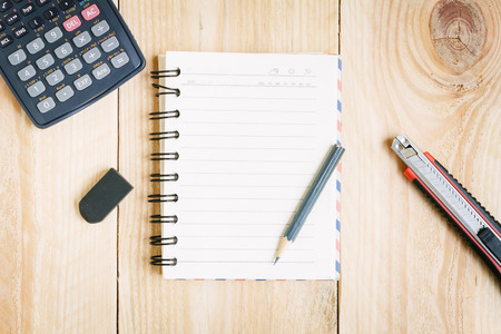 Notebook paper and school or office tools on vintage wood table for backgroundの写真素材