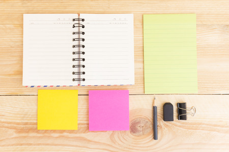 Notebook paper and school or office tools on wood table for background-vintage effectの写真素材