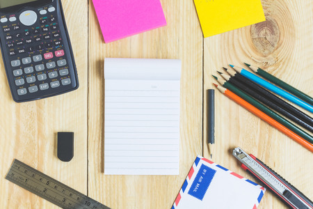 Notebook paper and school or office tools on wood table for backgroundの写真素材