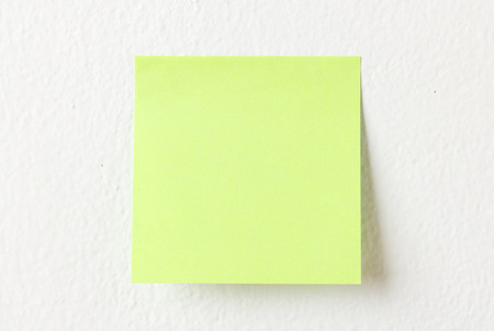 Yellow note pad on white wall backgroundの写真素材