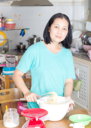 Asian woman chef cooking a bakery in kitchenの写真素材