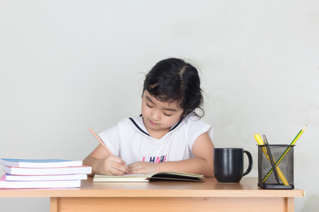 Beautiful little girl looking focused and concentrated on doing her homeworkの写真素材