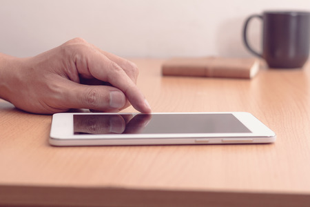 Smartphone or tablet computer male hand touching screen, vintage filter effectの写真素材