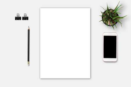 Top view of blank paper page on white table background office desk with smart phone and different objects. Minimal flat lay styleの写真素材