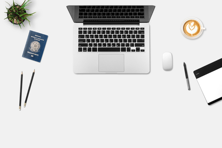 Modern workplace with notebook, little tree, passport book, pencil, graphic tablet and coffee cup copy space on gray background. Top view. Flat lay style.の写真素材