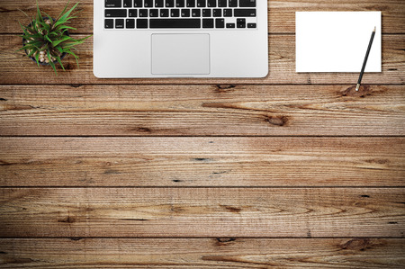 Modern workplace with notebook, tree, pencil and blank paper copy space on wood background. Top view. Flat lay style.の写真素材