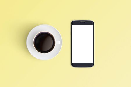 Top view of Cup of coffee in a white cup and smart phone on office desk backgroundの写真素材