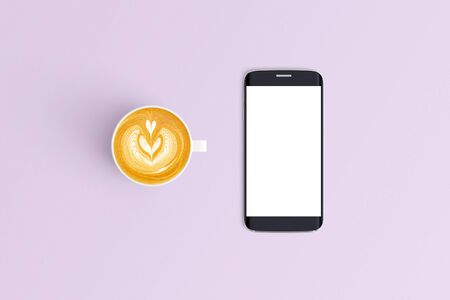 Top view of Cup of coffee in a white cup and smart phone on office desk backgroundの写真素材