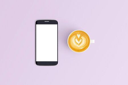 Top view of Cup of coffee in a white cup and smart phone on office desk backgroundの写真素材