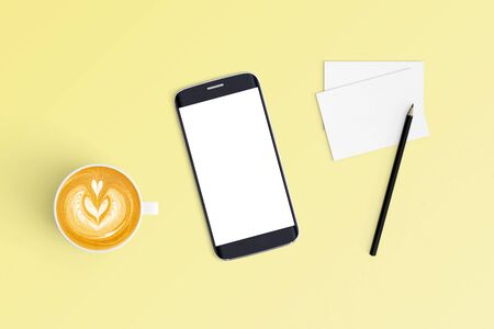 Top view of Cup of coffee in a white cup and smart phone on office desk backgroundの写真素材