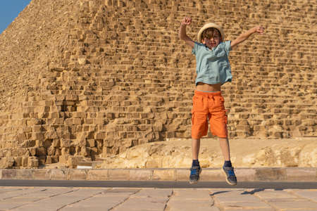 Happy boy jumping in front of the Cheops pyramid on the Giza plateau