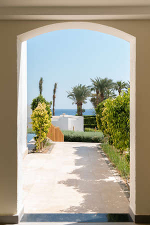 Seascape with trees, palms and road to sea through arch