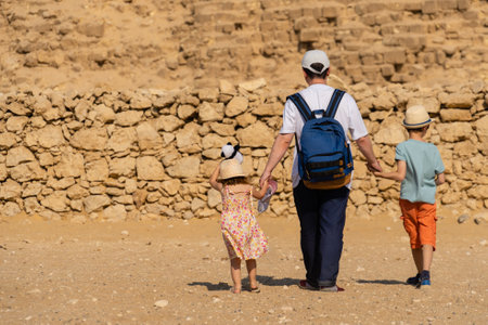 Father and children walk in front of the Chephren pyramid on the Giza plateauの写真素材