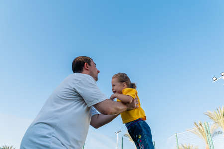 Happy father throwing up baby against blue sky