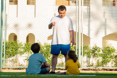 Father explaining children how to play footballの写真素材