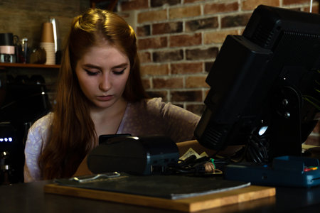 Concentrated young woman using smartphone during work in cafe