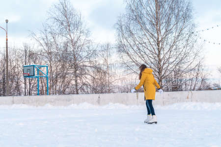 Young woman in yellow jacket skating at the rinkの写真素材