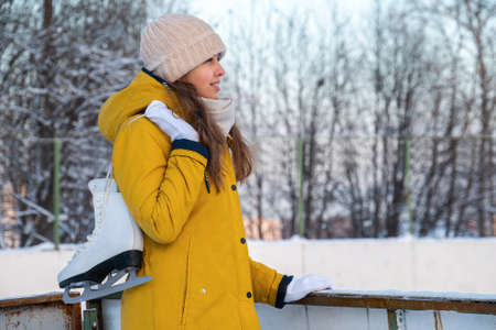 Portrait of young woman with ice skates looking to rinkの写真素材