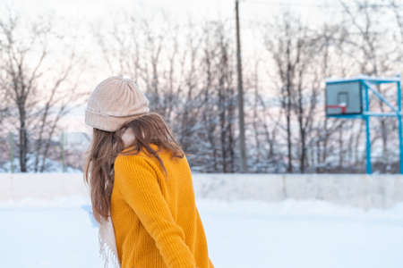 Portrait of happy young woman in yellow jacket skating at the rinkの写真素材