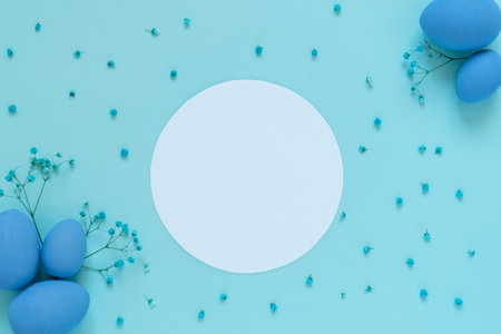 Easter composition with eggs and twigs of blue flowers and white circle frame in the middle