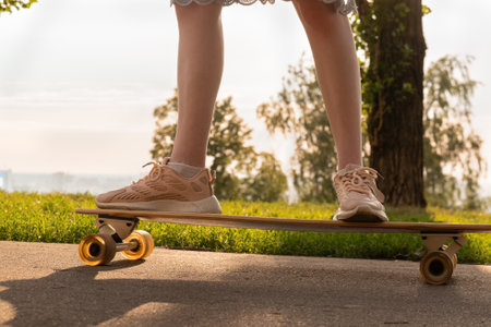 Crop faceless woman standing on longboard against summer skyの写真素材