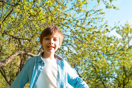Happy boy looking at camera against tree branchesの写真素材