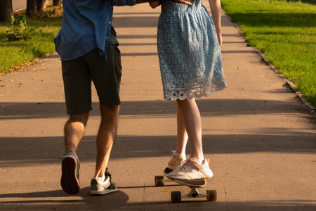 Crop faceless woman riding longboard and man running nearの写真素材