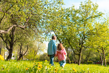 Cute siblings walking together along green parkの写真素材