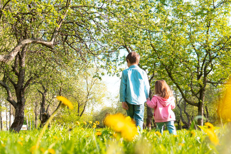 Cute siblings walking together along green parkの写真素材