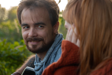 Portrait of charming young man looking at his girlfriend with smile. One shot in series of camping