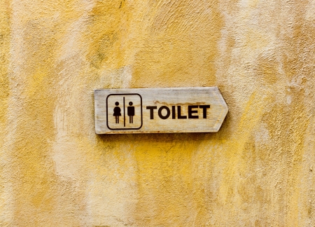Sign of public toilets WC in front of a yellow wall