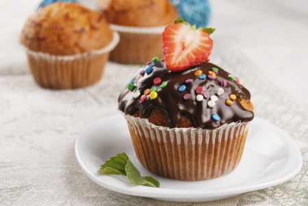 Chocolate sprinkle muffin with strawberry on top on the plateの写真素材