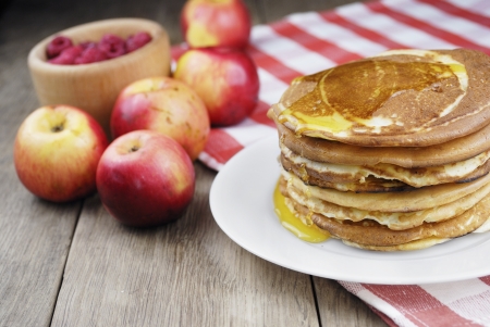 Pile of pancakes with berries in the white plate on the wooden tableの写真素材