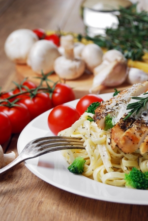 Pasta with fried chicken on the wooden table with vegetablesの写真素材