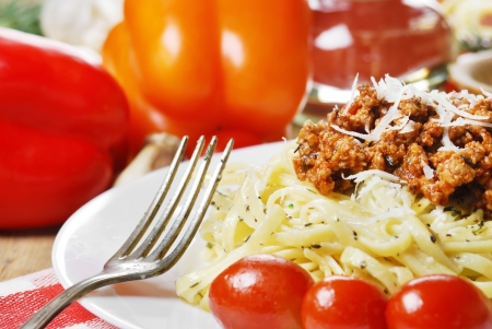 Pasta bolognese in the white plate on the wooden table with vegetablesの写真素材